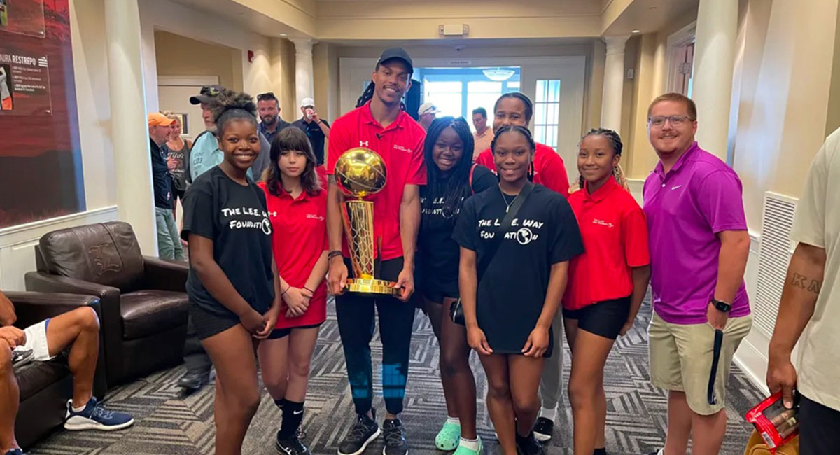 Damion Lee posing with Larry O'Brien trophy with kids