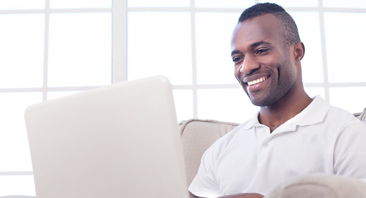 African American man in white shirt looking at laptop