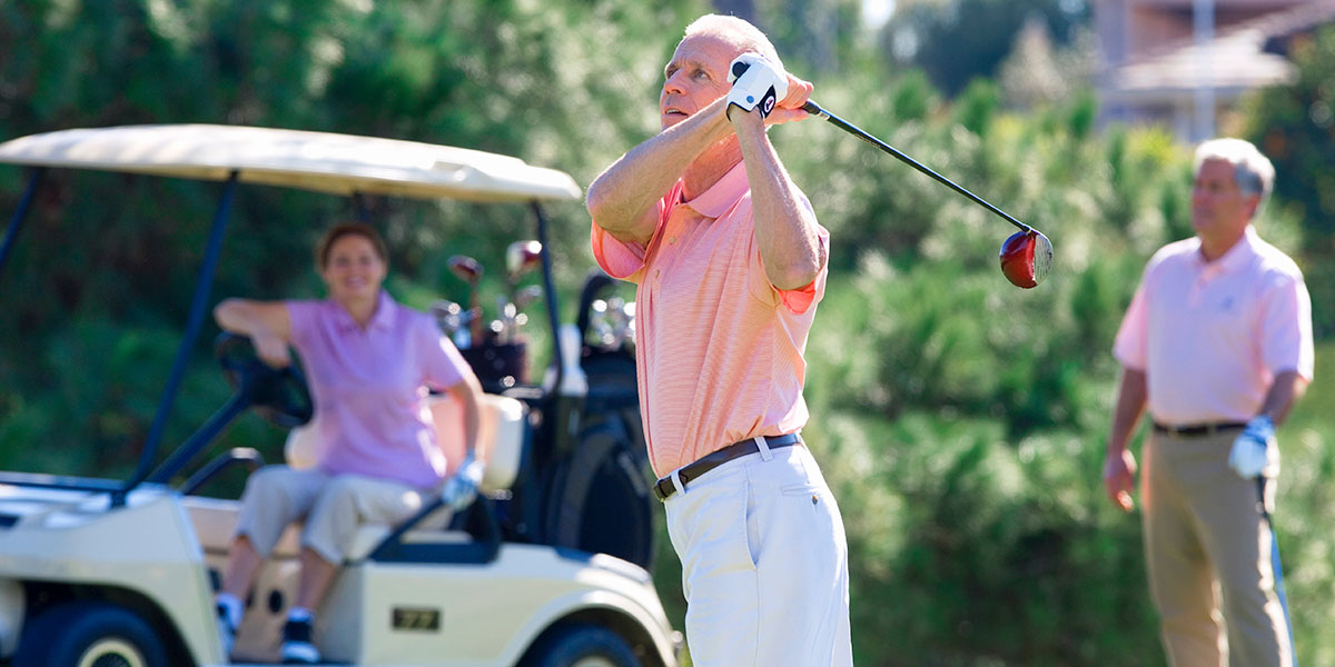 three golfers wearing pink and white golfing attire, playing a charity golf tournament with social distancing.