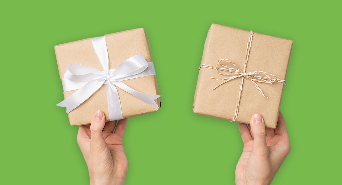 Female hands holding up gift boxes in front of green screen