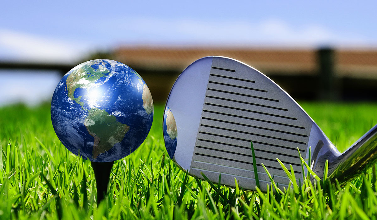 Closeup of golf club next to a globe on a tee